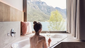 Eine Person in einer Badewanne mit Blick auf Berge und einen See.
