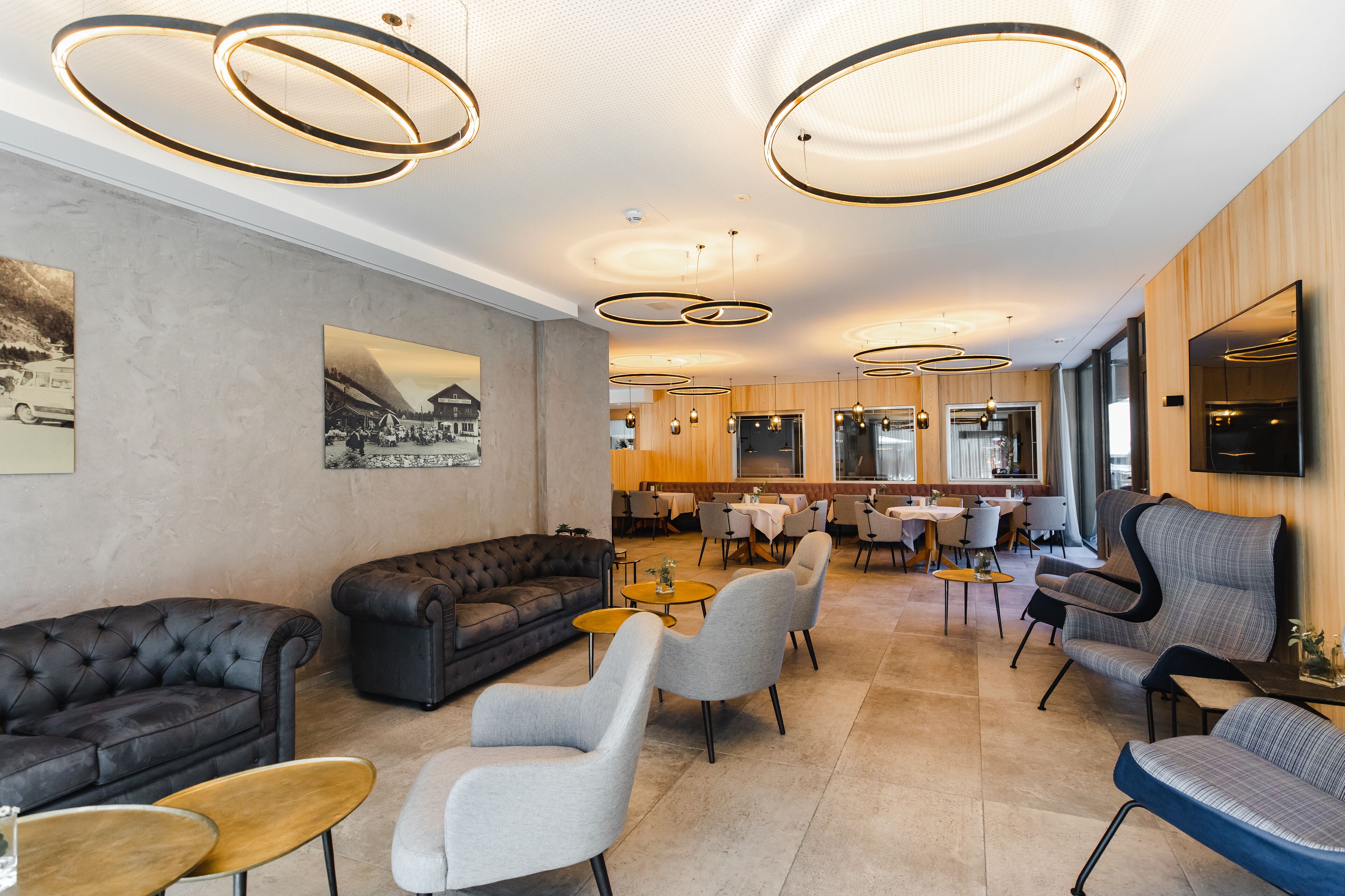 A modern hotel lobby with a seating area, a bar, and a dining area.