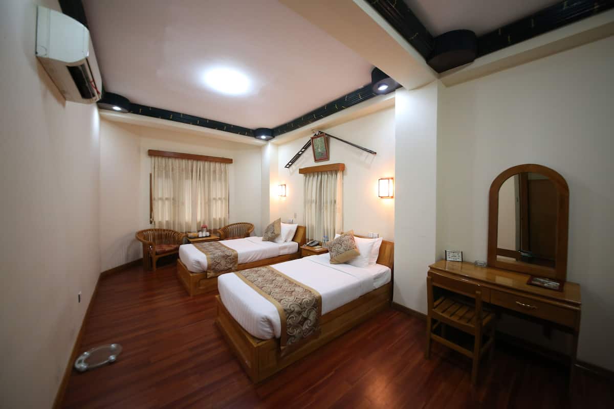 A hotel room with two beds, a wooden desk, a chair, and a mirror.
