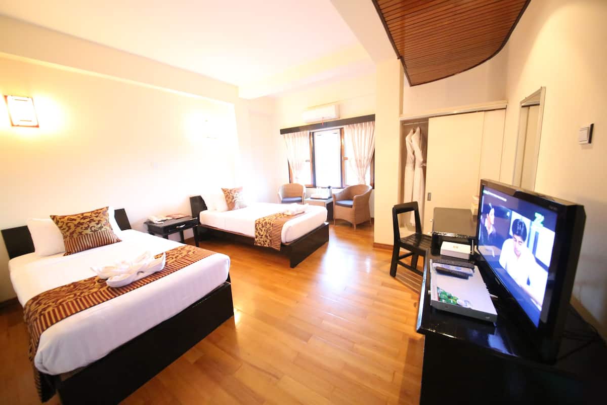 A hotel room with two beds, a TV, and a desk with a laptop.