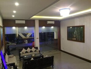A modern living room with a sofa set, a coffee table, and a large window. - Olympic Hotel (Yangon)
