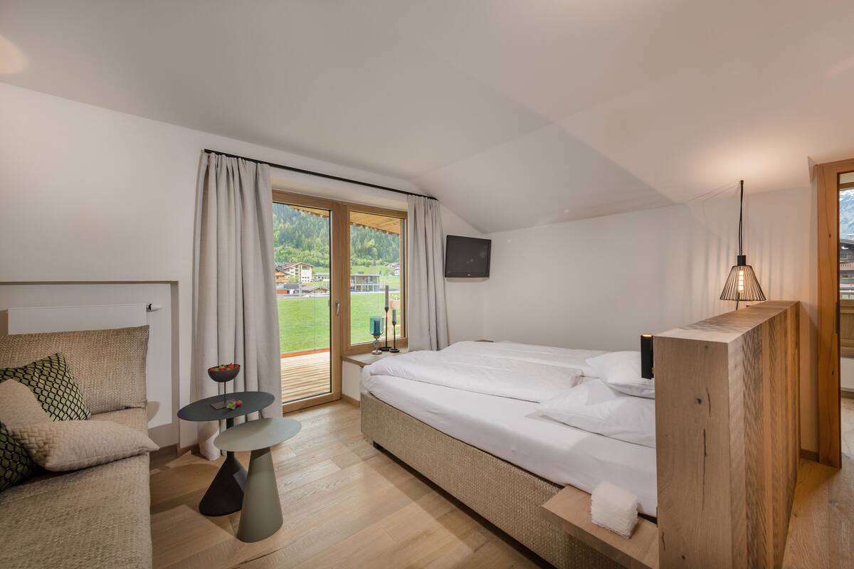 Une chambre moderne avec un grand lit, un canapé, une petite table et un téléviseur.
