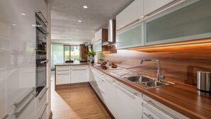 Una cucina moderna con mobili bianchi, un piano di lavoro in legno, elettrodomestici in acciaio inossidabile e un'ampia finestra.