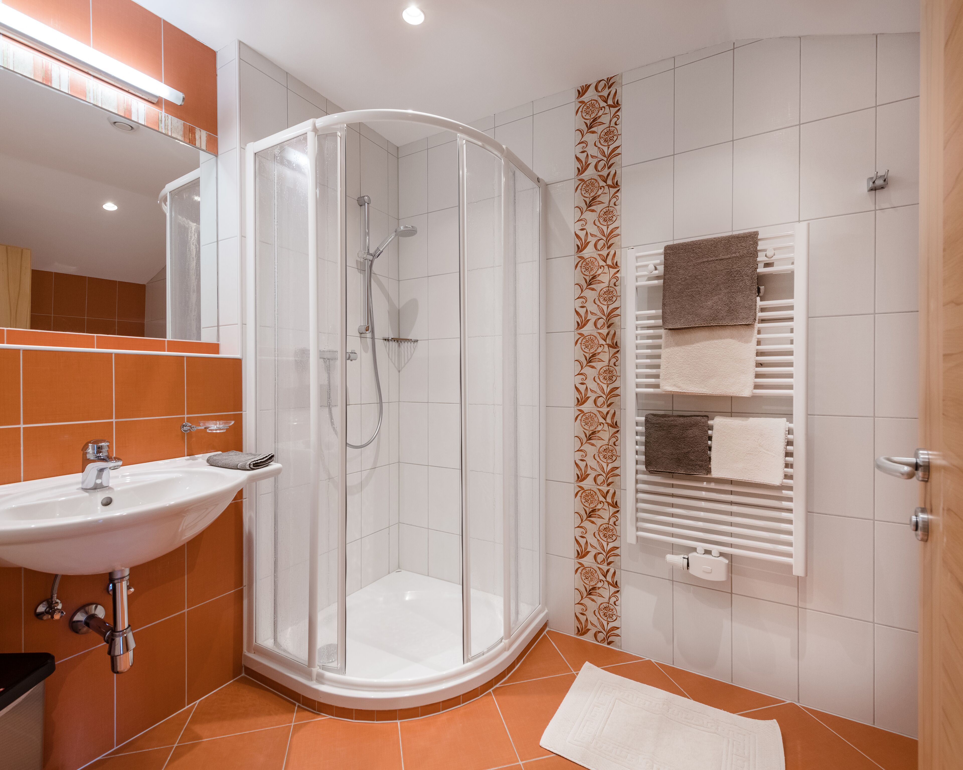 A modern bathroom with a glass-enclosed shower, a sink, and a towel rack with multiple towels.