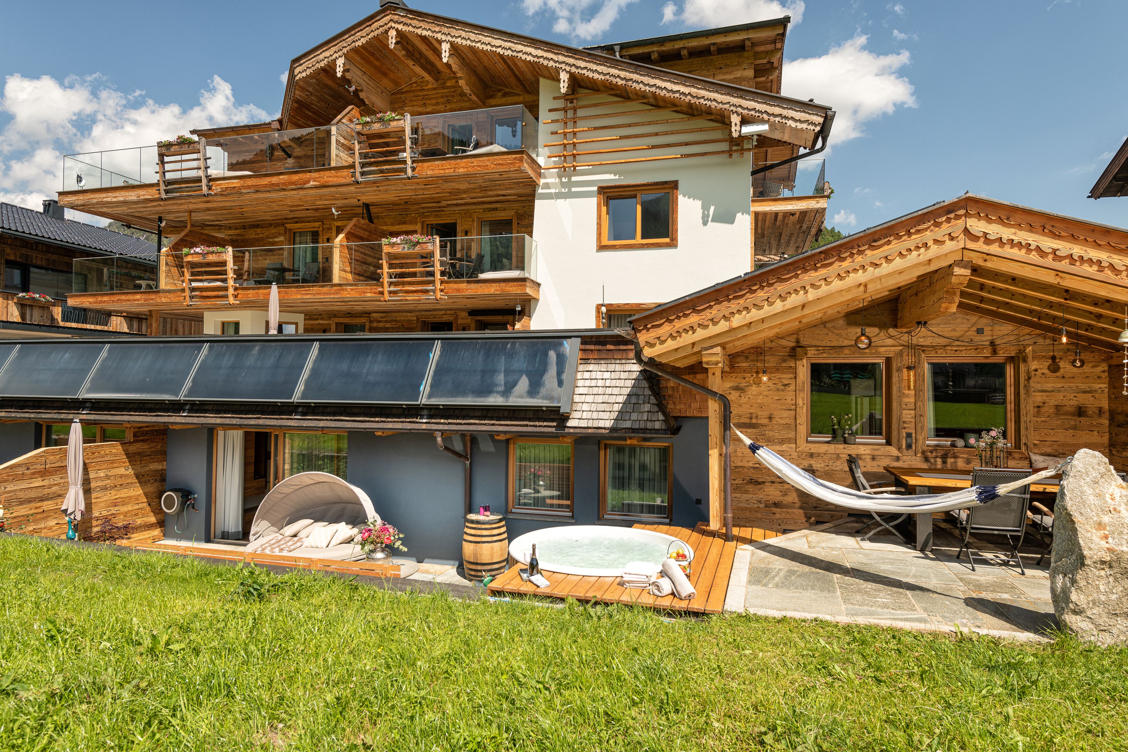 Un chalet en bois à plusieurs étages, doté d’un balcon, d’un jacuzzi et d’un hamac.