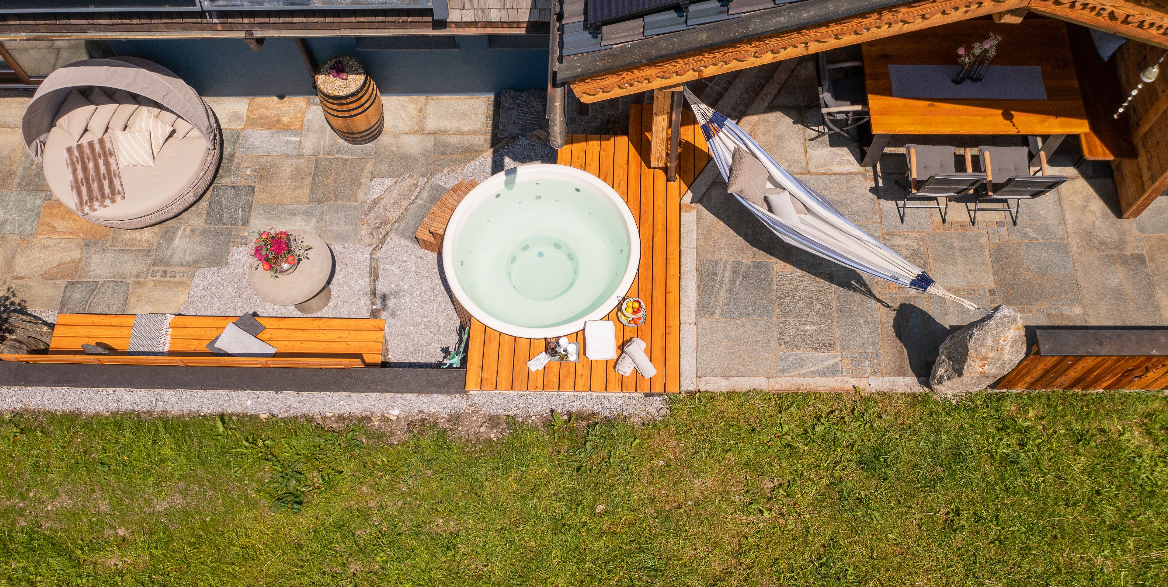 A rooftop terrace with a hot tub, a hammock, and a wooden deck.