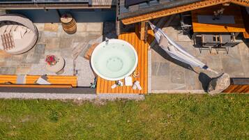 A rooftop terrace with a hot tub, a hammock, and a wooden deck.