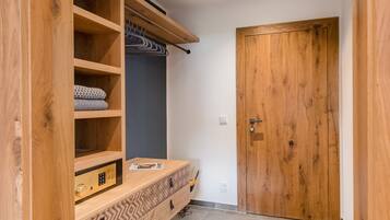 Un armario de madera con múltiples estantes y un banco integrado, una puerta de madera y piso de baldosas.