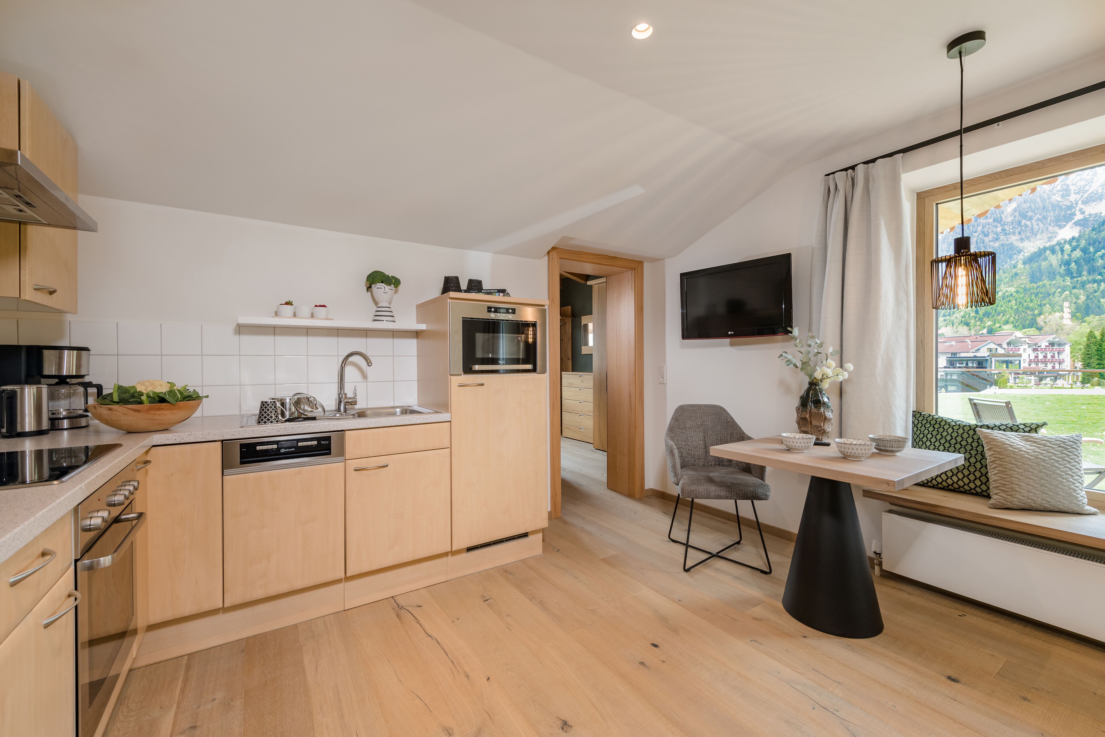 Eine moderne Küche mit Holzausstattung, einem eingebauten Backofen und einem Essbereich mit Tisch und Stühlen.