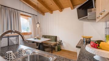 A modern kitchen with a granite countertop, stainless steel sink, and wooden ceiling beams.