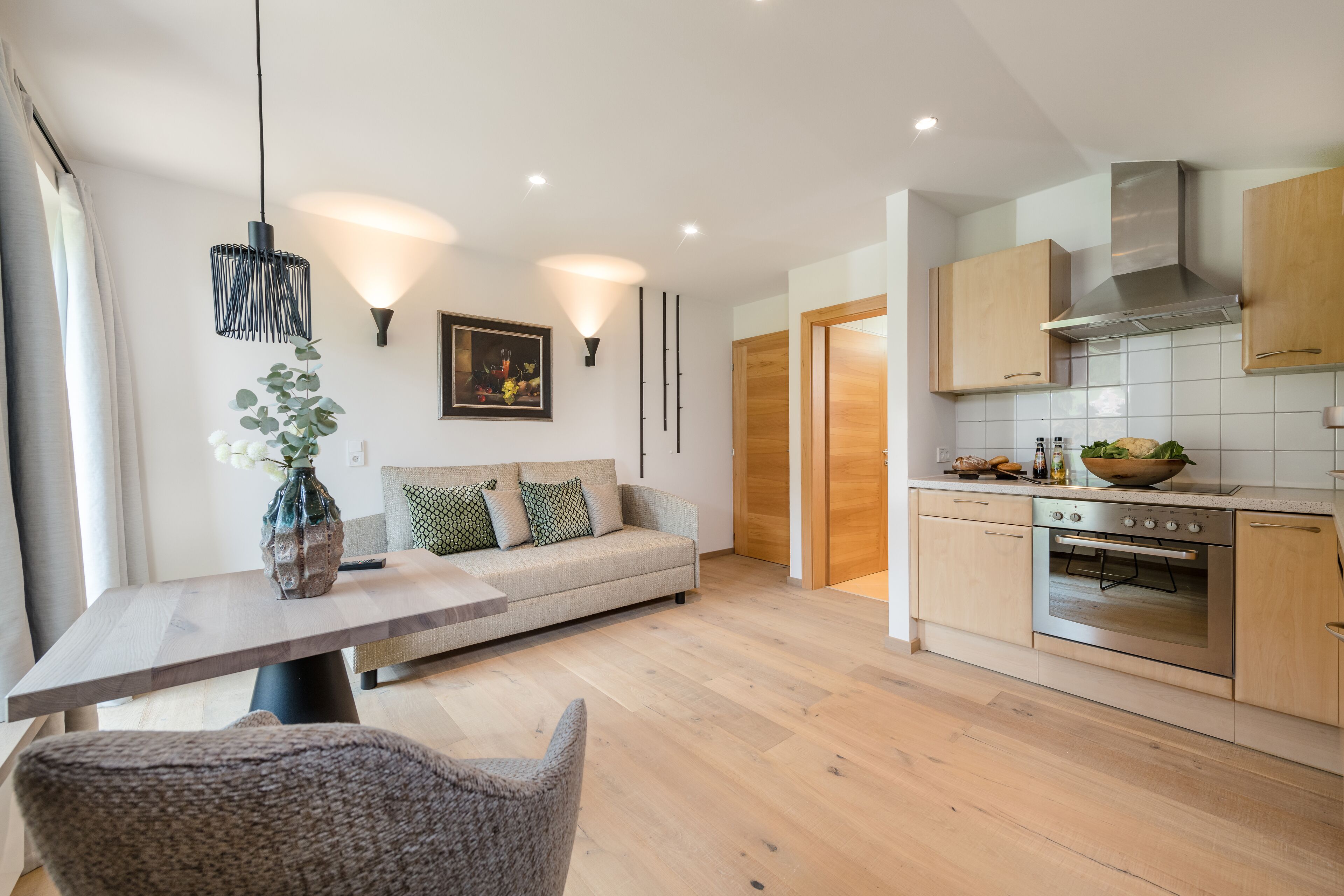A modern kitchen with wooden cabinets, a built-in oven, and a dining area with a table and chairs.