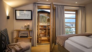 Una camera accogliente con un letto, un piccolo angolo salotto con un cuscino, un comodino in legno e un cartello incorniciato appeso al muro.