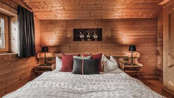 Un dormitorio de cabaña de madera con una cama grande, dos mesitas de noche y un cuadro enmarcado en la pared.