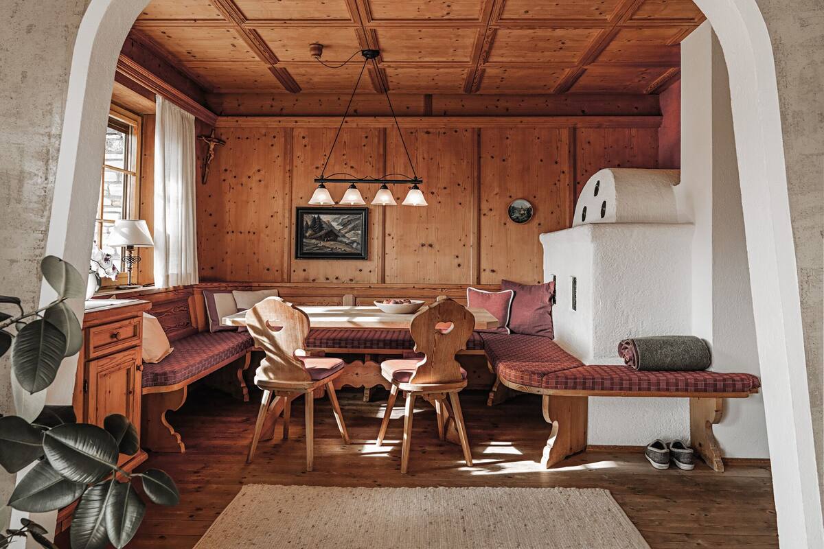 Un intérieur chaleureux et rustique, avec une table à manger en bois, des bancs et un réfrigérateur blanc.