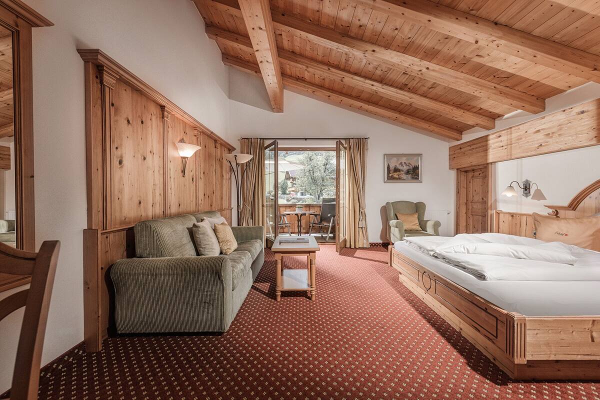 Une pièce chaleureuse avec un plafond en bois, un lit, un canapé et une table.