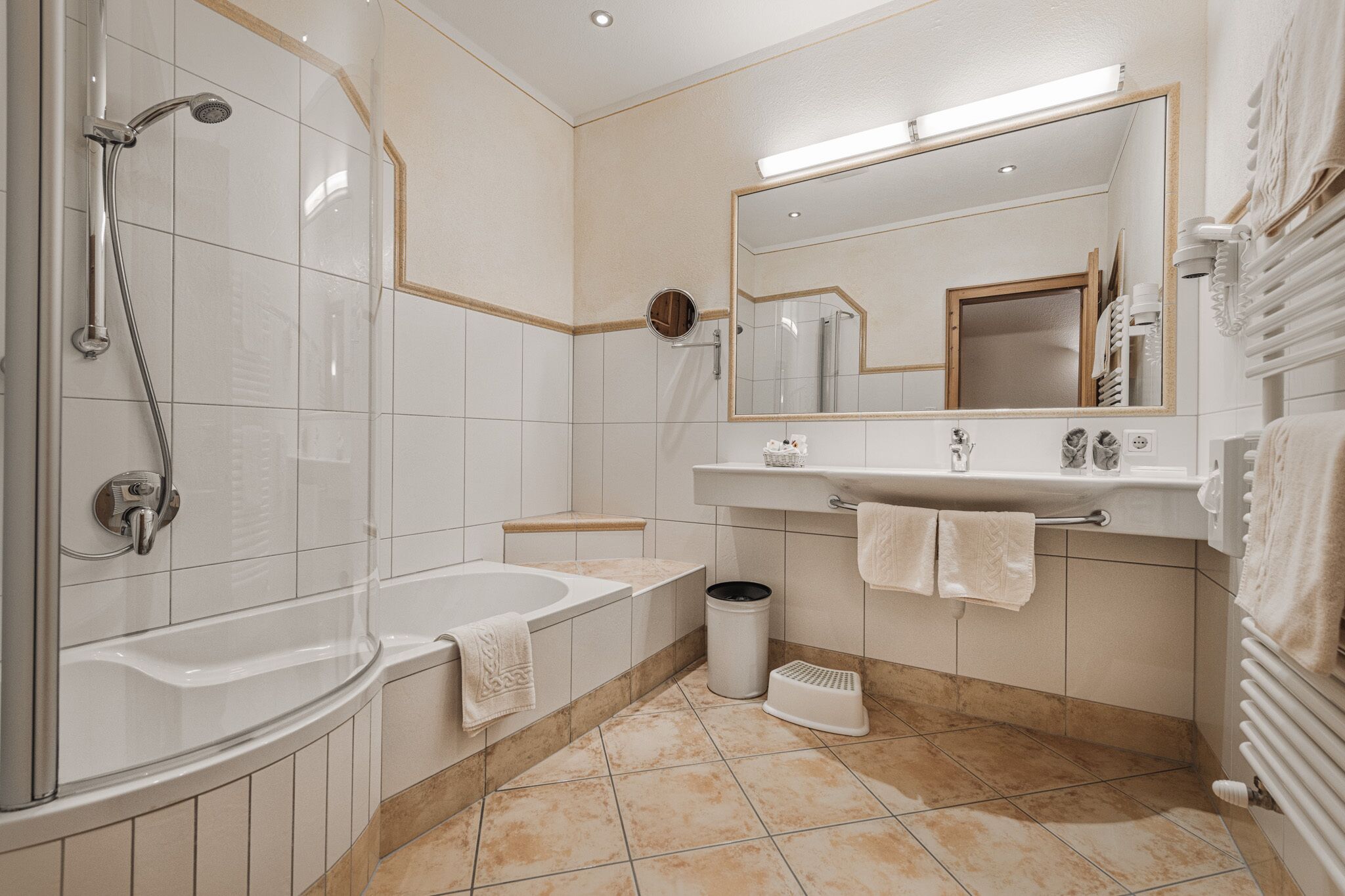 Un baño moderno con bañera, ducha y un espejo grande.