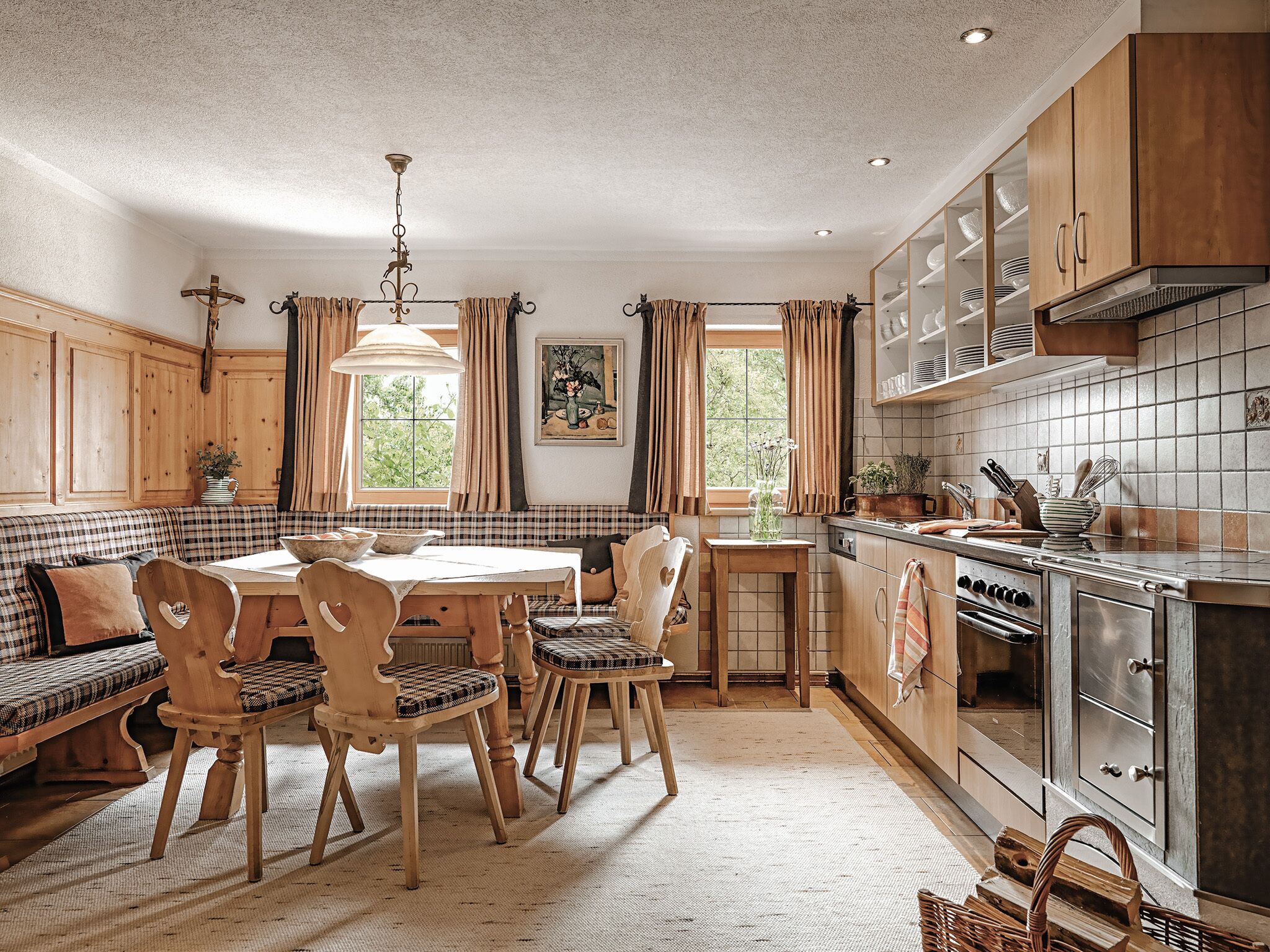 A cozy kitchen with wooden cabinets, a dining table with chairs, a bench, and a hanging light fixture.