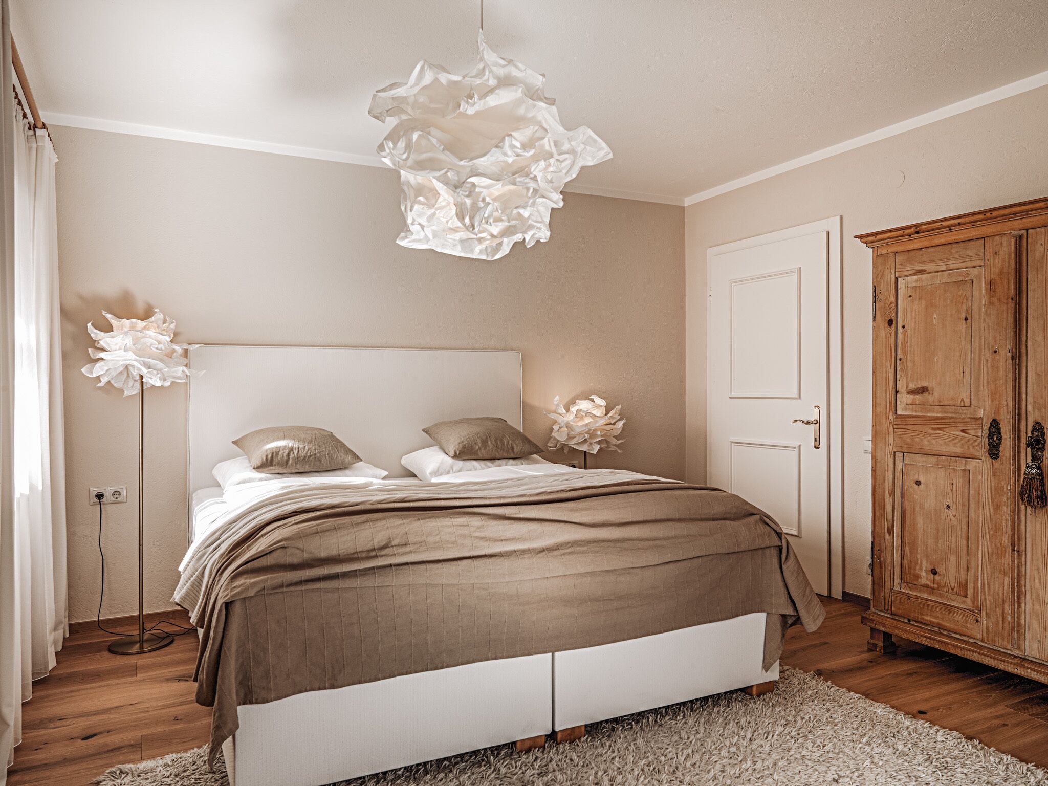 A bedroom with a bed, bedside lamps, a wardrobe, and a floor lamp.