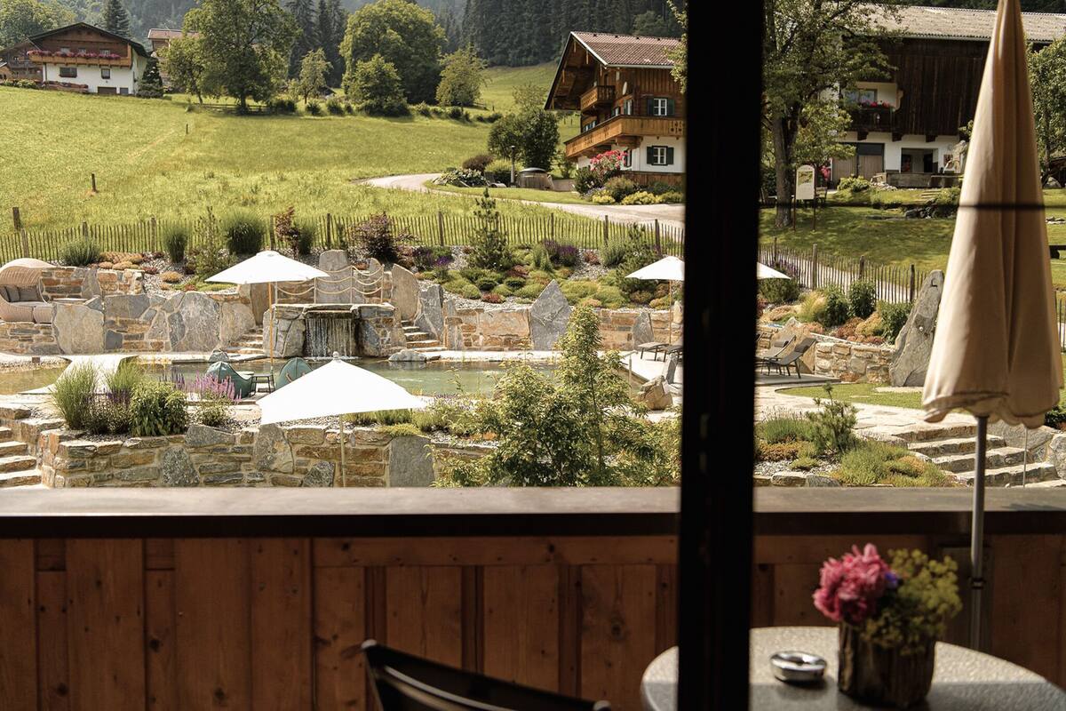 Vue d’un restaurant doté d’une terrasse donnant sur un jardin aménagé et un vignoble.