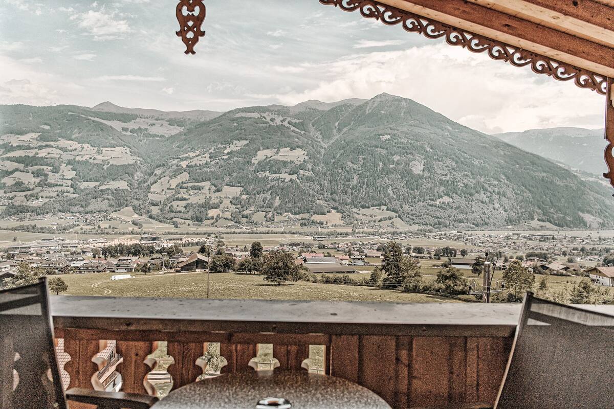 Un balcon offrant une vue sur un paysage montagneux et un village situé en contrebas.