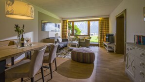 A modern living room with a dining area, a sofa, a coffee table, and a television.