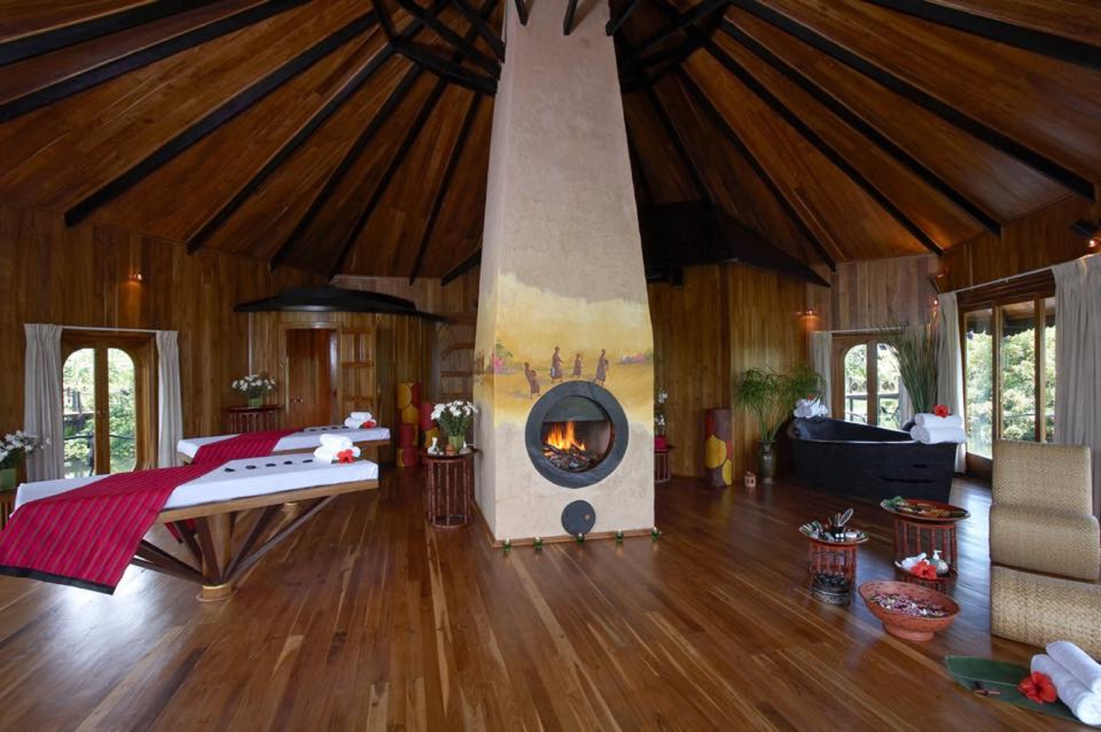 A spacious room with a large fireplace, wooden floors, and a cozy seating area.