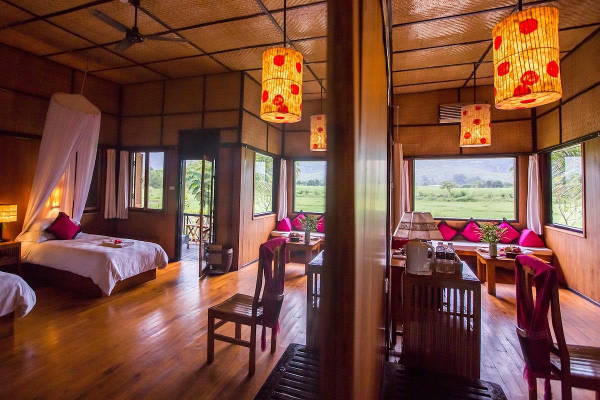 A room with a bed, a chair, a table, and a view of the outdoors.