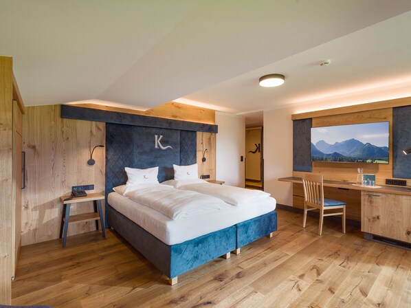Un dormitorio moderno con una cama grande, un escritorio y vistas a montañas.