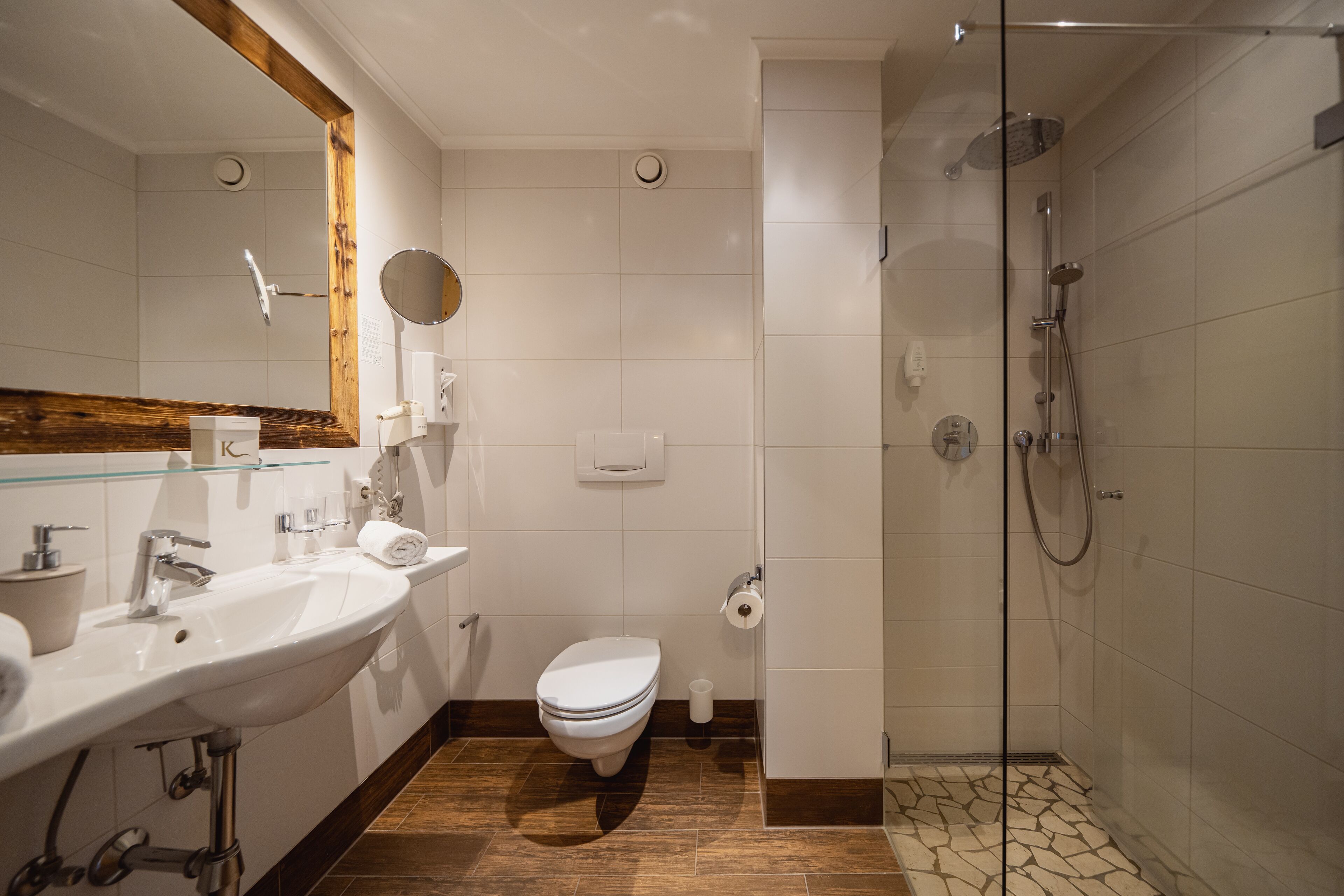 A modern bathroom with a large sink, toilet, and glass-enclosed shower.