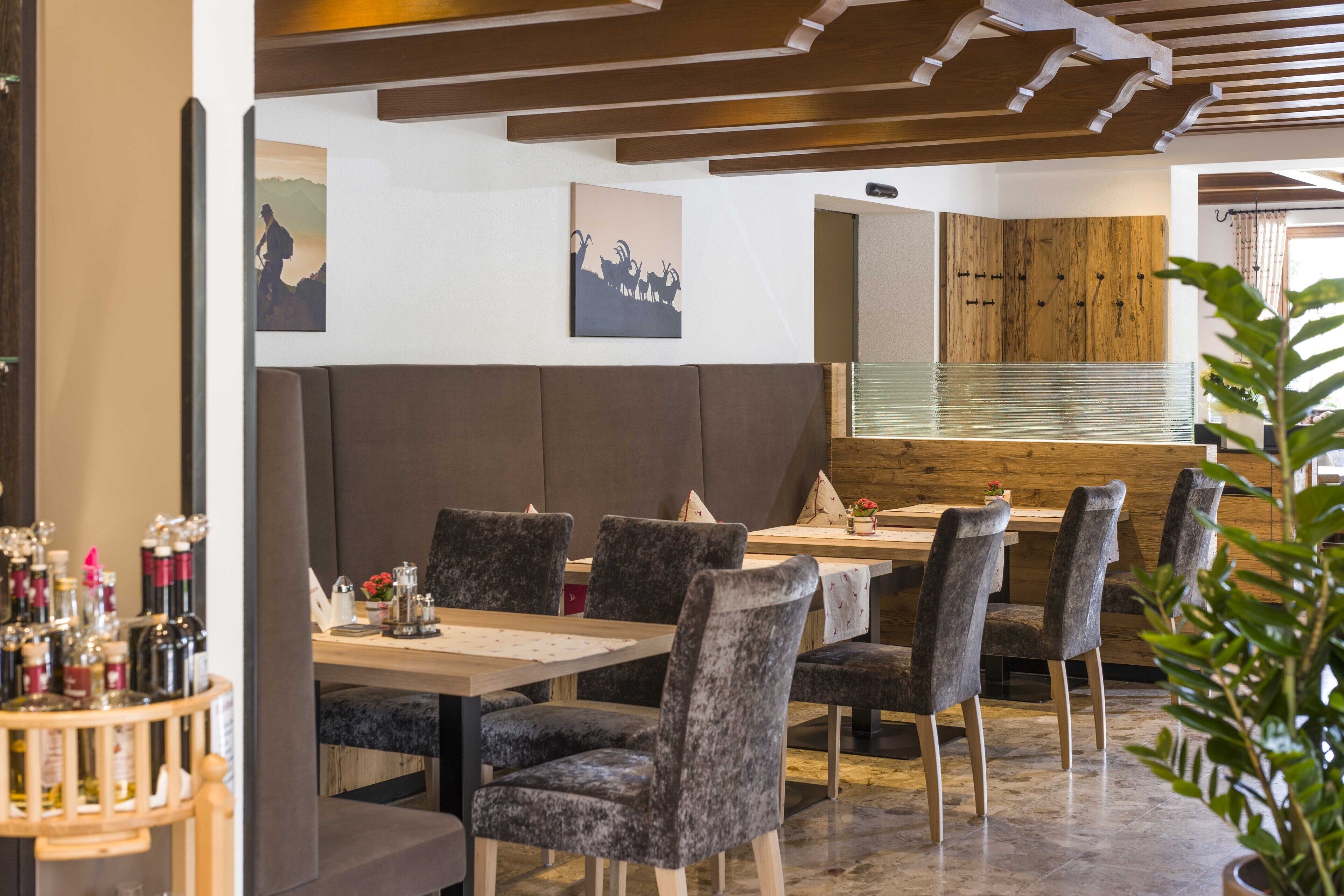 Ein Restaurantinneres mit Holzbalkendecke, dunklen Polsterbänken und einer Bar mit Flaschen.