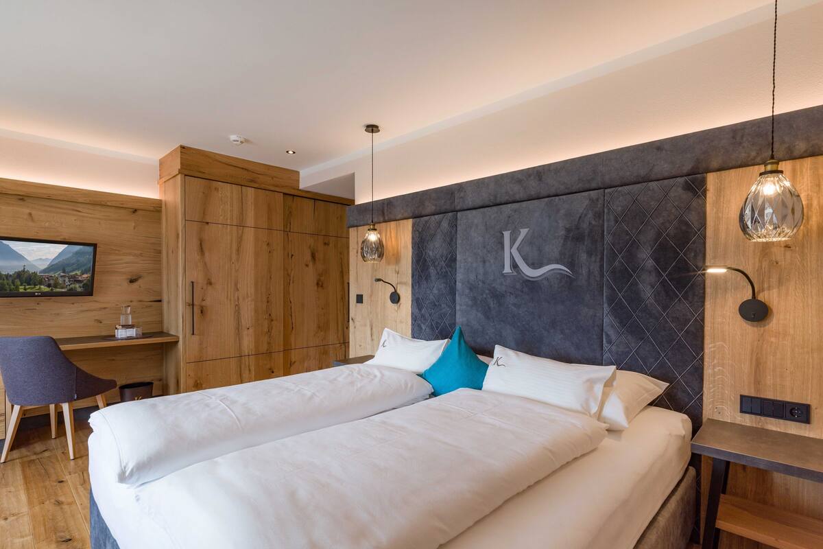 A modern hotel room with a large bed, a desk, and a television on the wall.