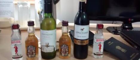 Un escritorio con varias botellas de licor, un monitor de computadora y una carpeta negra.
