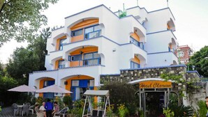 A multi-story hotel with balconies, outdoor seating, and a garden area. - Hotel Clarion (Lalitpur)