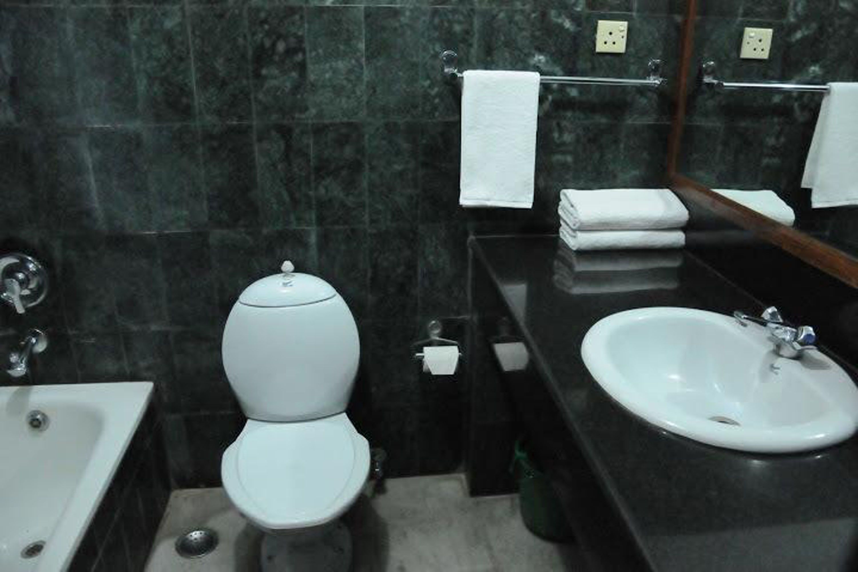 A bathroom with a toilet, sink, and mirror.
