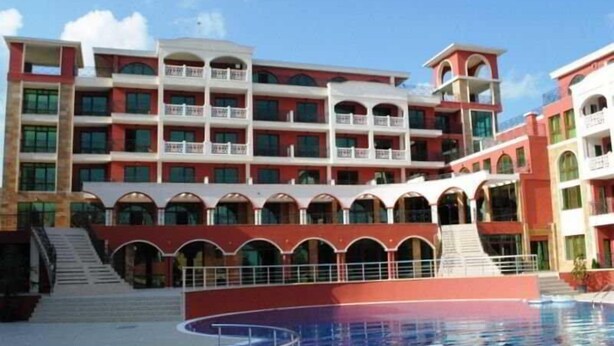 A multi-story hotel with a swimming pool, balconies, and a red and white color scheme. - St George Palace (ST VLAS)