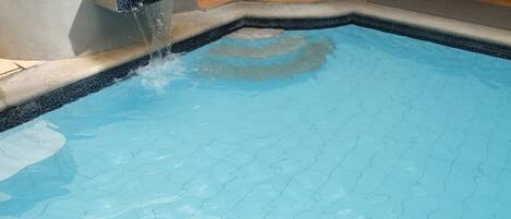 Una piscina con agua cristalina y borde de azulejos.