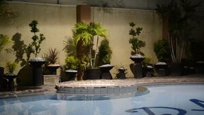 A swimming pool with a tiled edge, surrounded by potted plants and a concrete wall. - DM Residente Inns and Villas (Angeles City)