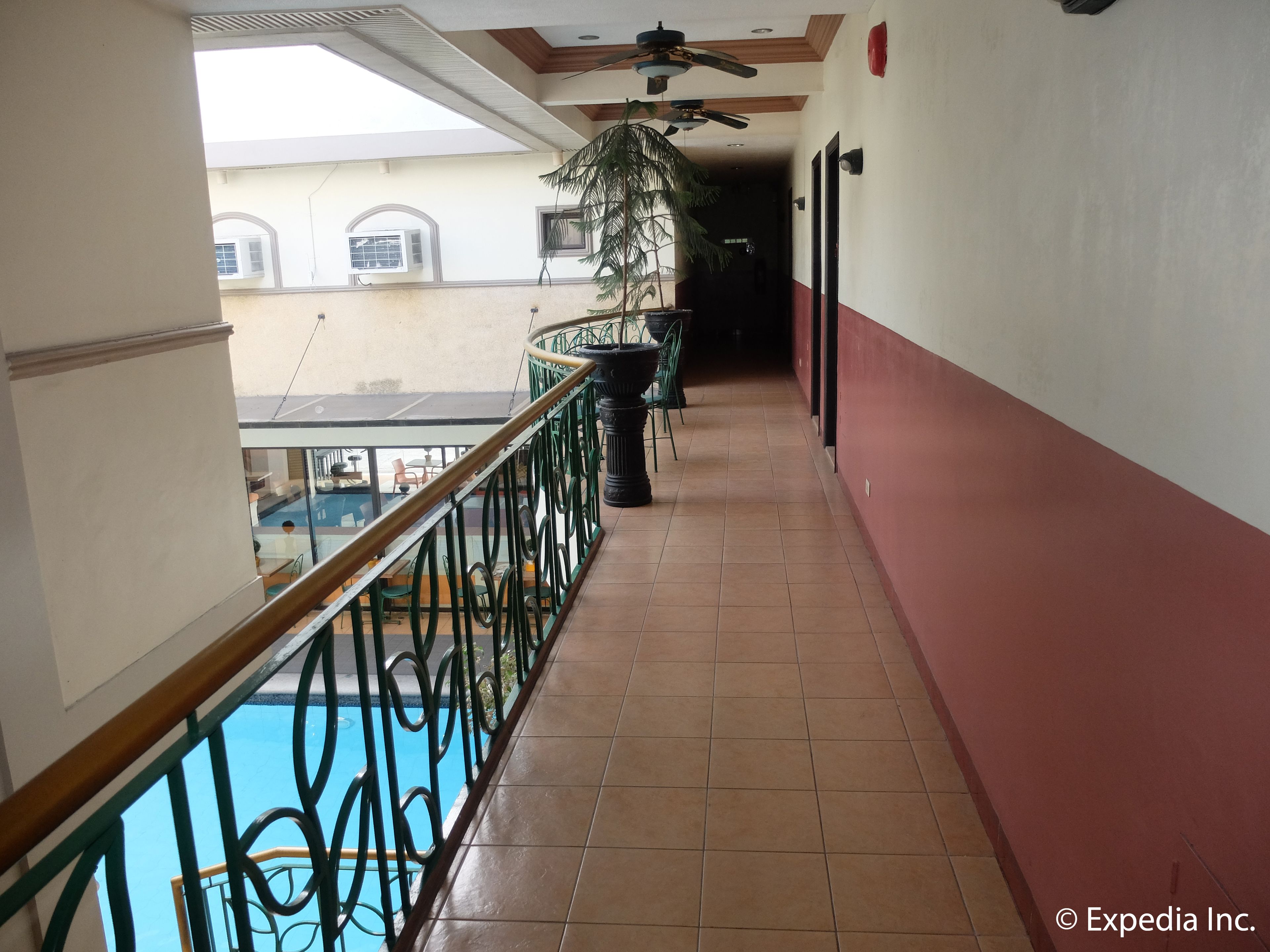 A corridor with a tiled floor, a metal railing, and a ceiling fan.