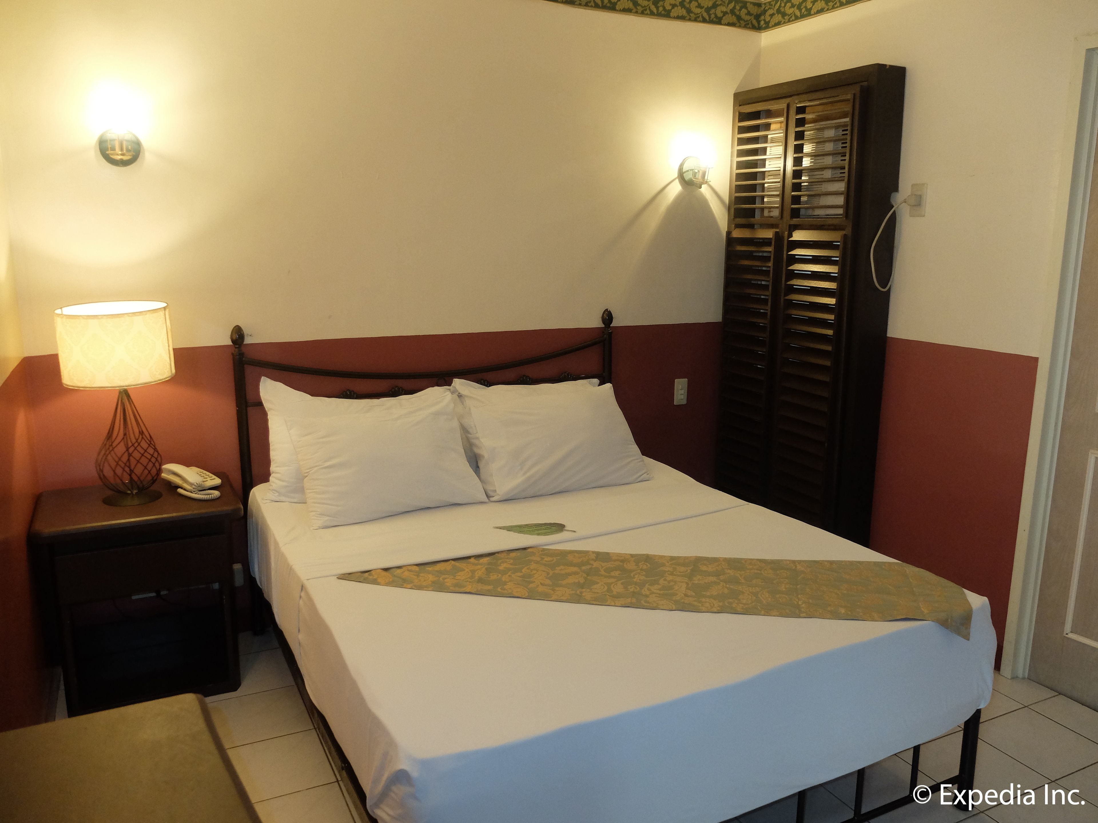 A neatly made bed with white linens, a bedside lamp, and a telephone on a nightstand.