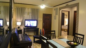 A living room with a television, a sofa, a dining table, and a ceiling fan. - DM Residente Inns and Villas (Angeles City)