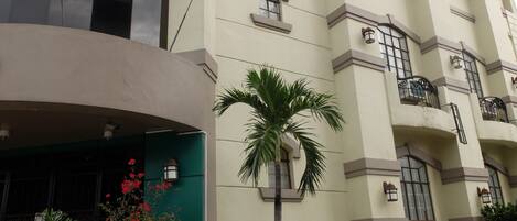 A multi-story building with a curved facade, balconies, and potted plants.
