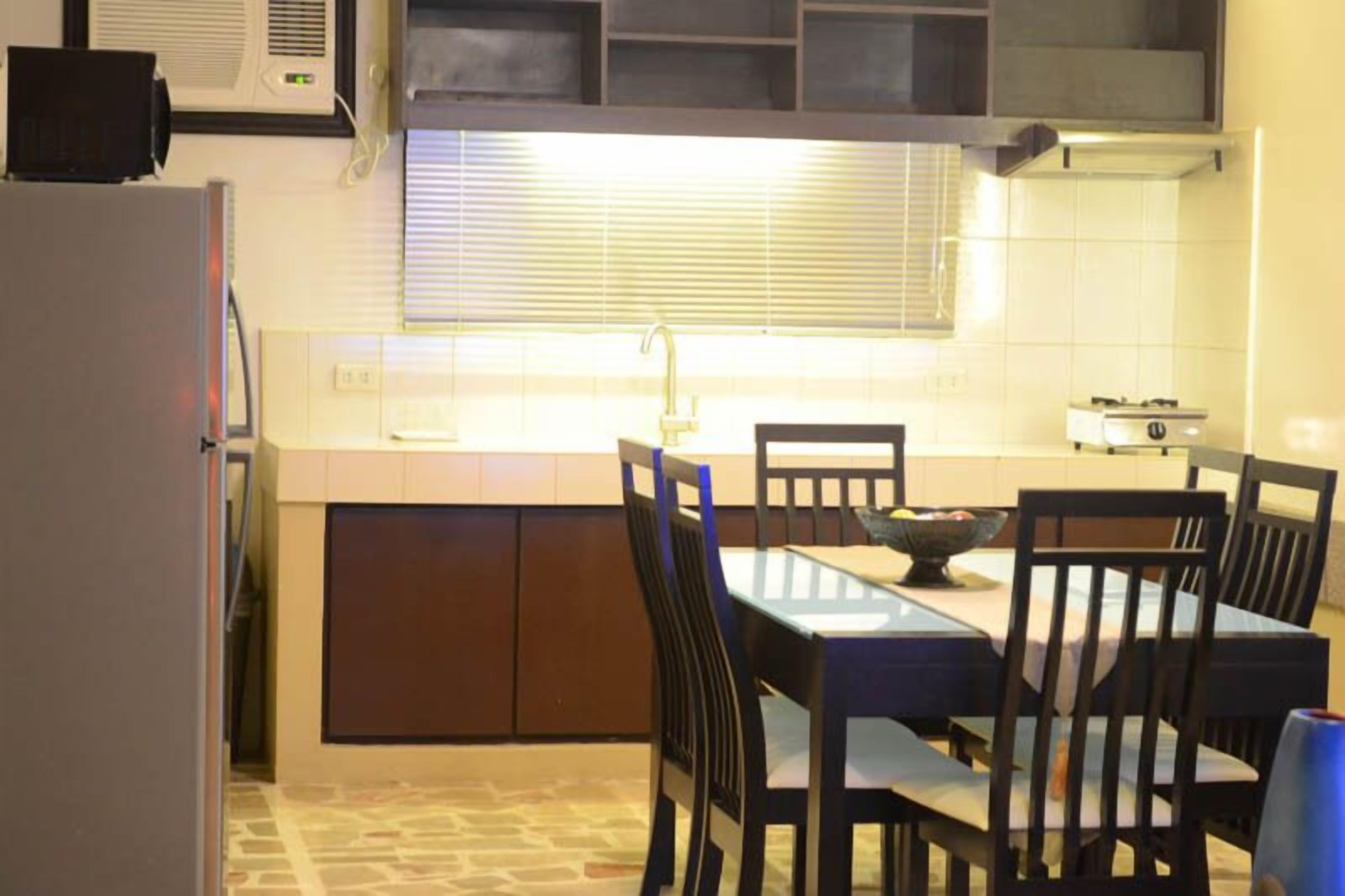 Una cocina compacta con una mesa y sillas, estufa integrada y una ventana con persianas.