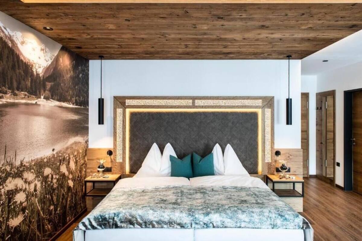 A bedroom with a large bed, wooden ceiling, and a mural of a mountain landscape.
