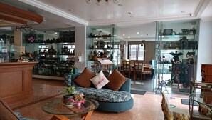 A spacious living area with a glass coffee table, comfortable seating, and a display of collectibles. - Golden Pine Hotel (Baguio)