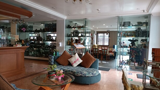 A spacious living area with a glass coffee table, comfortable seating, and a display of collectibles. - Golden Pine Hotel (Baguio)
