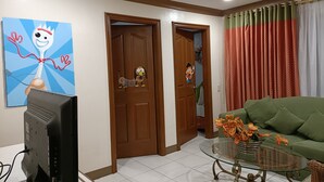 A living room with a green sofa, a glass coffee table, and a painting on the wall. - Golden Pine Hotel (Baguio)