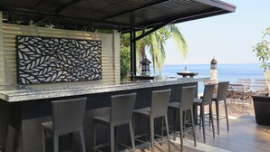 A bar area with a stone countertop, wicker chairs, and a view of the ocean. - Aiyanar Beach and Dive Resort (Mabini)