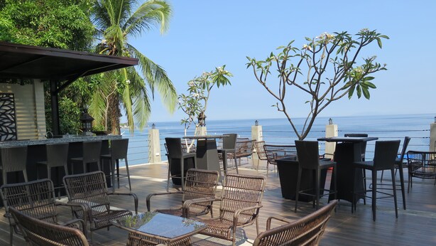 An outdoor seating area with wicker furniture and a bar, overlooking the ocean. - Aiyanar Beach and Dive Resort (Mabini)
