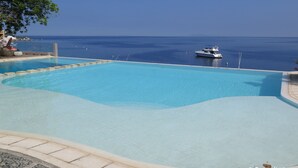 A clear blue pool with a view of the ocean and a boat in the distance. - Aiyanar Beach and Dive Resort (Mabini)