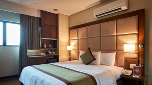 Une chambre d’hôtel avec un grand lit, une table de chevet avec un téléphone, une lampe et un mini-bar.